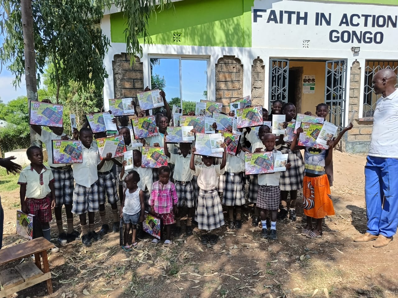 hero-img-01 Child receiving educational writing materials from Faith in Action Kenya Gongo CBO